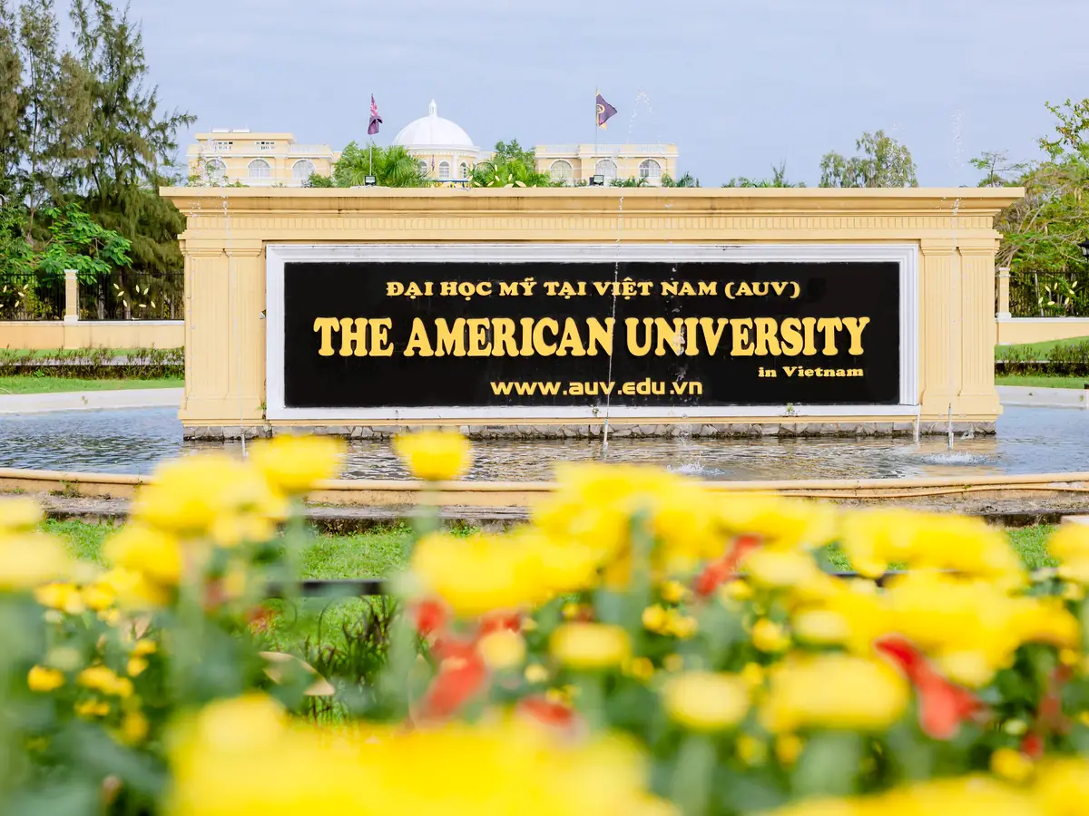 The AUV sign by the entrance fountain, with yellow flowers in front