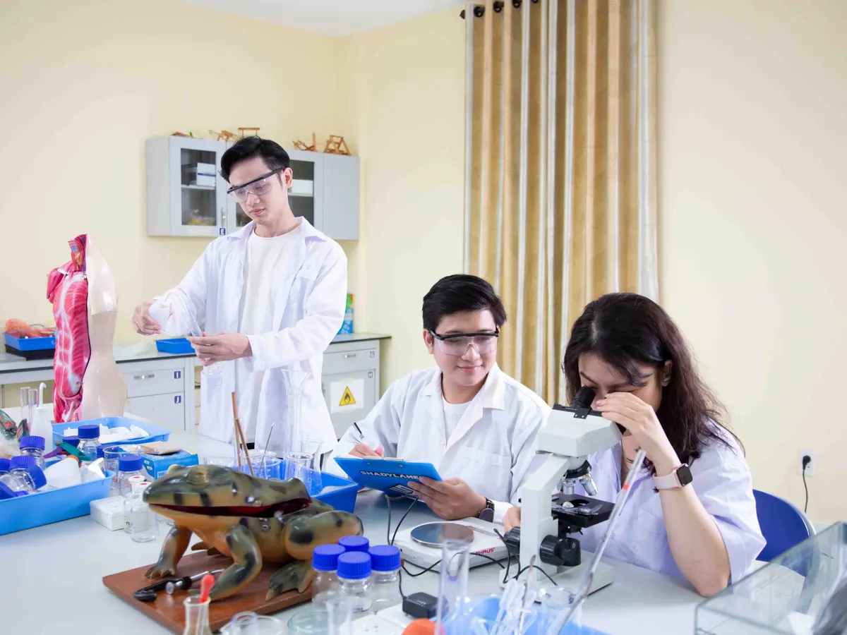 Students in lab coats working with a microscope and anatomy models