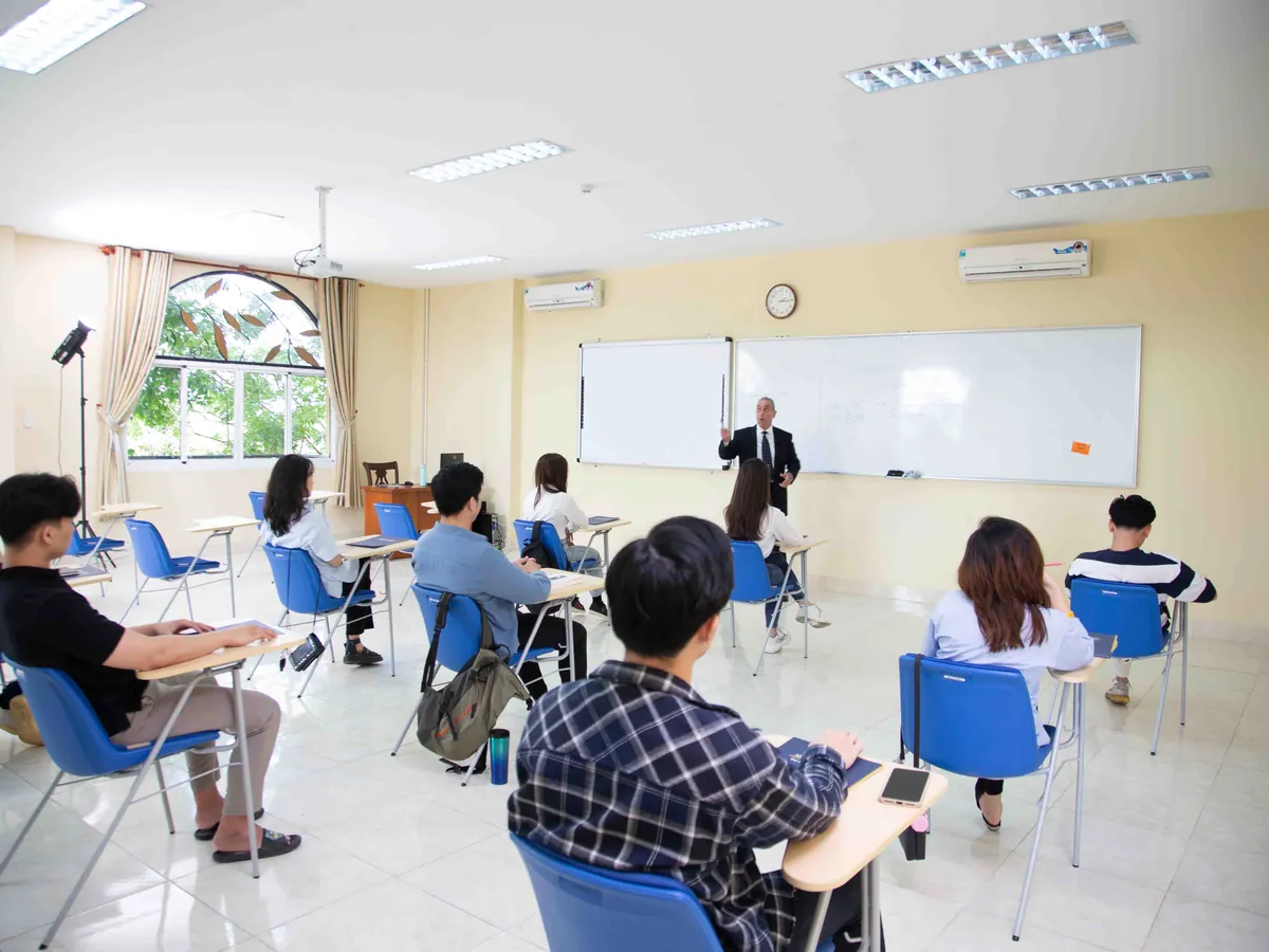 A professor teaches at the board in a bright AUV classroom